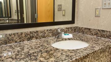 A bathroom with a granite countertop, a white sink, and a large mirror.