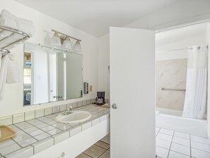A bathroom with a white sink, a mirror, a towel rack, and a shower area.