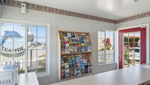 A room with a large window, a bulletin board with travel brochures, and a sign with a dolphin and the number 1106. - Discovery Inn (Seaside)