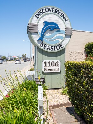 A Discovery Inn sign with a dolphin logo, the address 1106 Fremont, and a street view with cars and greenery.