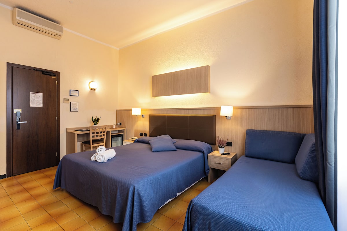 Una habitación de hotel con dos camas, un escritorio y una silla.