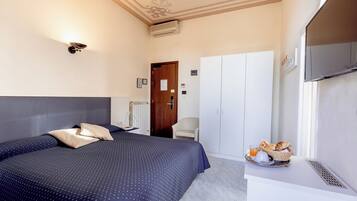 A hotel room with a bed, a desk with breakfast, a wardrobe, and a television.