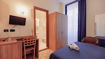 Une chambre d’hôtel comprenant un lit, un bureau, une chaise, une armoire, une télévision et une salle de bain.