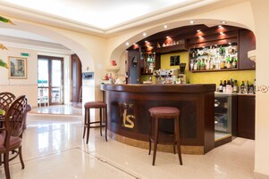 Una zona de bar con mostrador, taburetes y una exhibición de botellas.