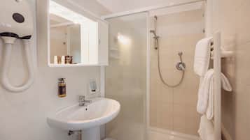 Un baño con lavamanos blanco, un espejo, secador de pelo, ducha y toallero.