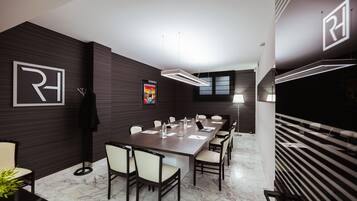 A modern conference room with a long table, chairs, and a projector screen.