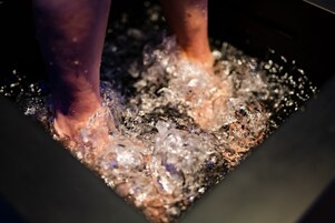 Primer plano de pies en un líquido burbujeante, probablemente una bañera de hidromasaje o spa.