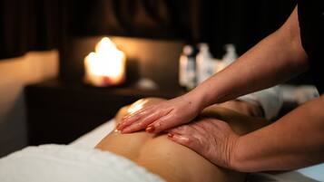A massage therapy session with a candle in the background.