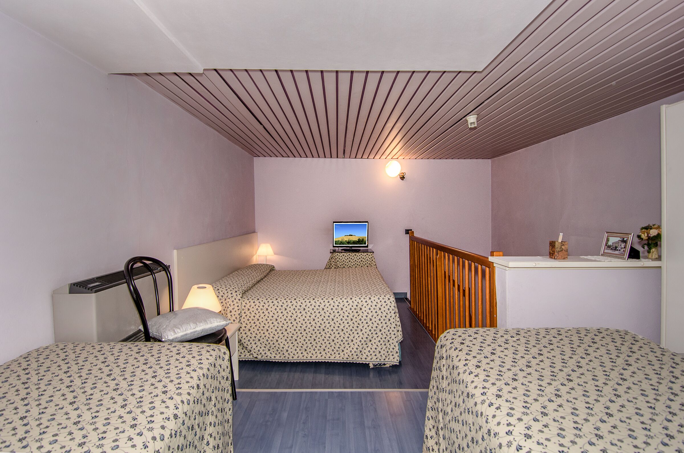 Une chambre à coucher comprenant un lit, deux tables de chevet, un bureau, une chaise, une lampe et un téléviseur.