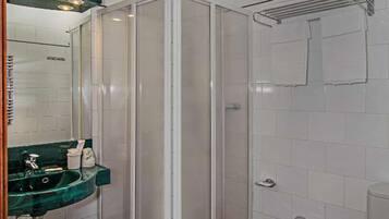 Een badkamer met een douchecabine van glas, een wastafel met een groene marmeren blad, een bidet en een toilet.