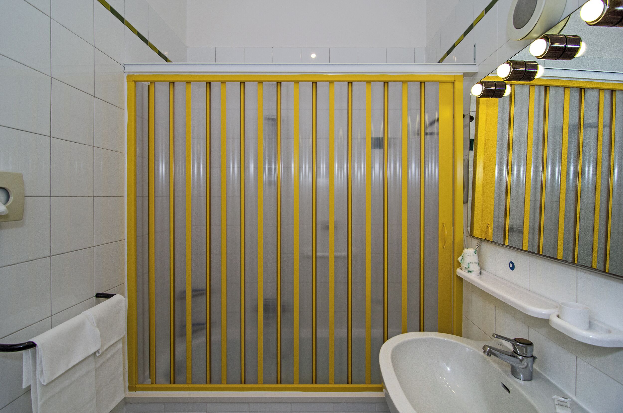 Un baño con cabina de ducha, lavamanos y espejo.