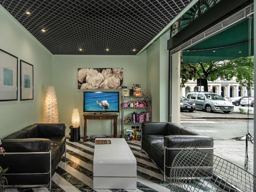 Eine Hotellobby mit großem Fernseher, schwarzen Ledersofas, einem Marmorboden und gerahmten Bildern an der Wand.