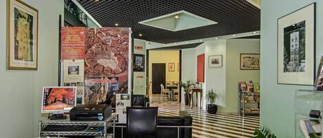A hotel lobby with a check-in counter, seating area, and a reception desk.