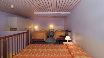 Ein Schlafzimmer mit zwei Betten, einem Holgeländer, einem Schreibtisch mit Lampe und einem an der Wand befestigten Regal.