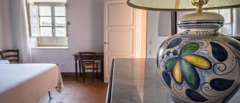 Una habitación con una cama, una mesa con una lámpara decorativa, una ventana y una puerta.