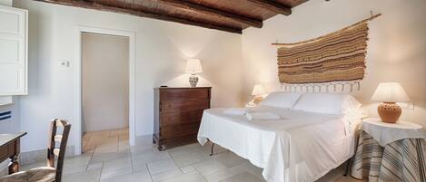 Un dormitorio con cama, cómoda de madera y una mesa con lámpara.