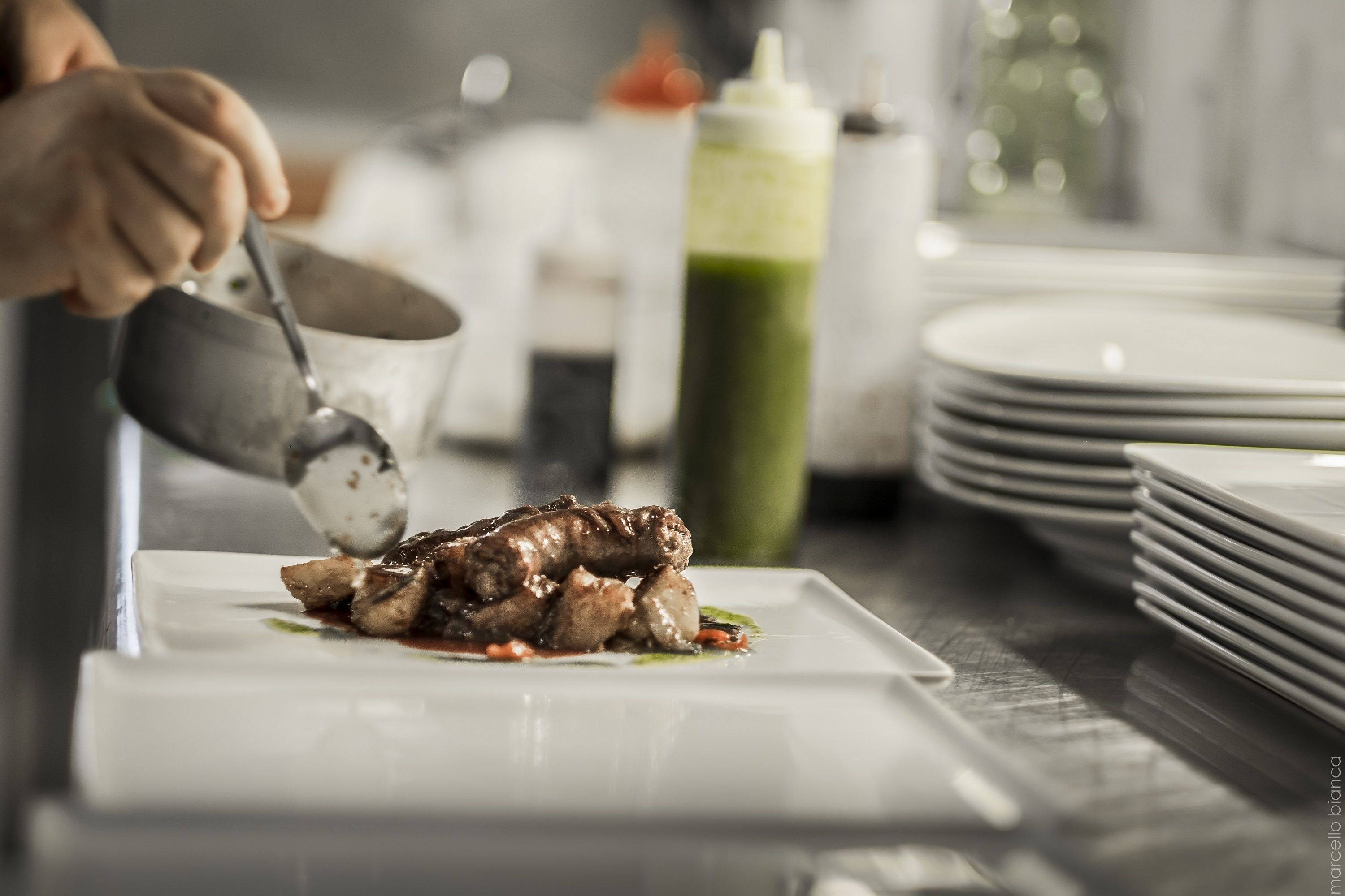 A chef plating food on a white plate.