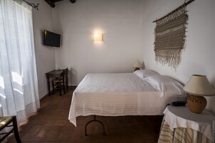 Una camera da letto con un letto, lampade da comodino, una TV a muro, un tavolino con lampada e una sedia.