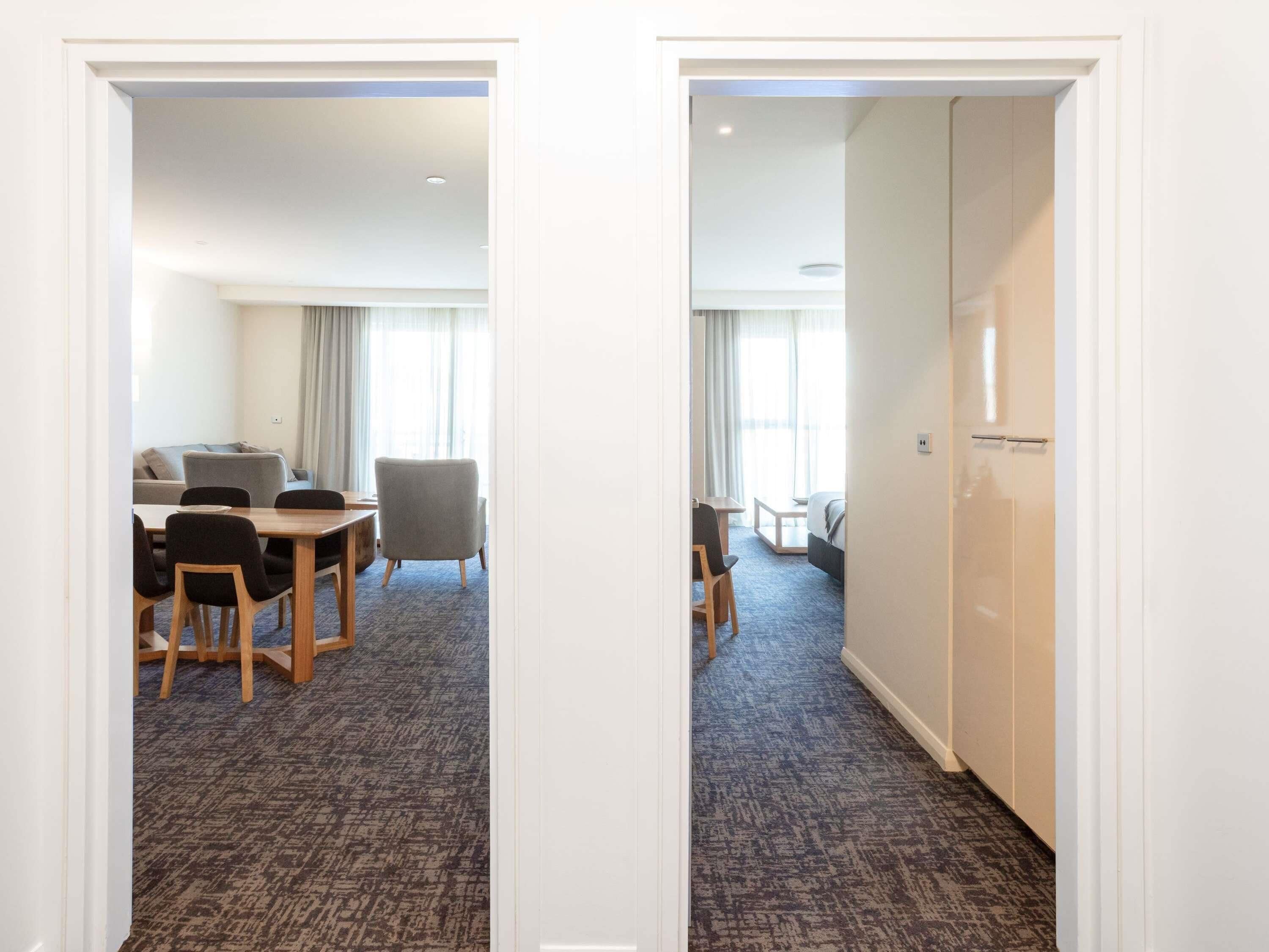 A hotel room with a dining area, a bed, a desk, and a wardrobe.