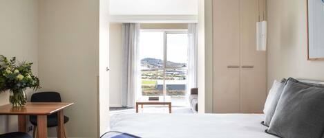 Ein Hotelzimmer mit Bett, Schreibtisch mit Stuhl, Fenster mit Blick und einem Kleiderschrank.