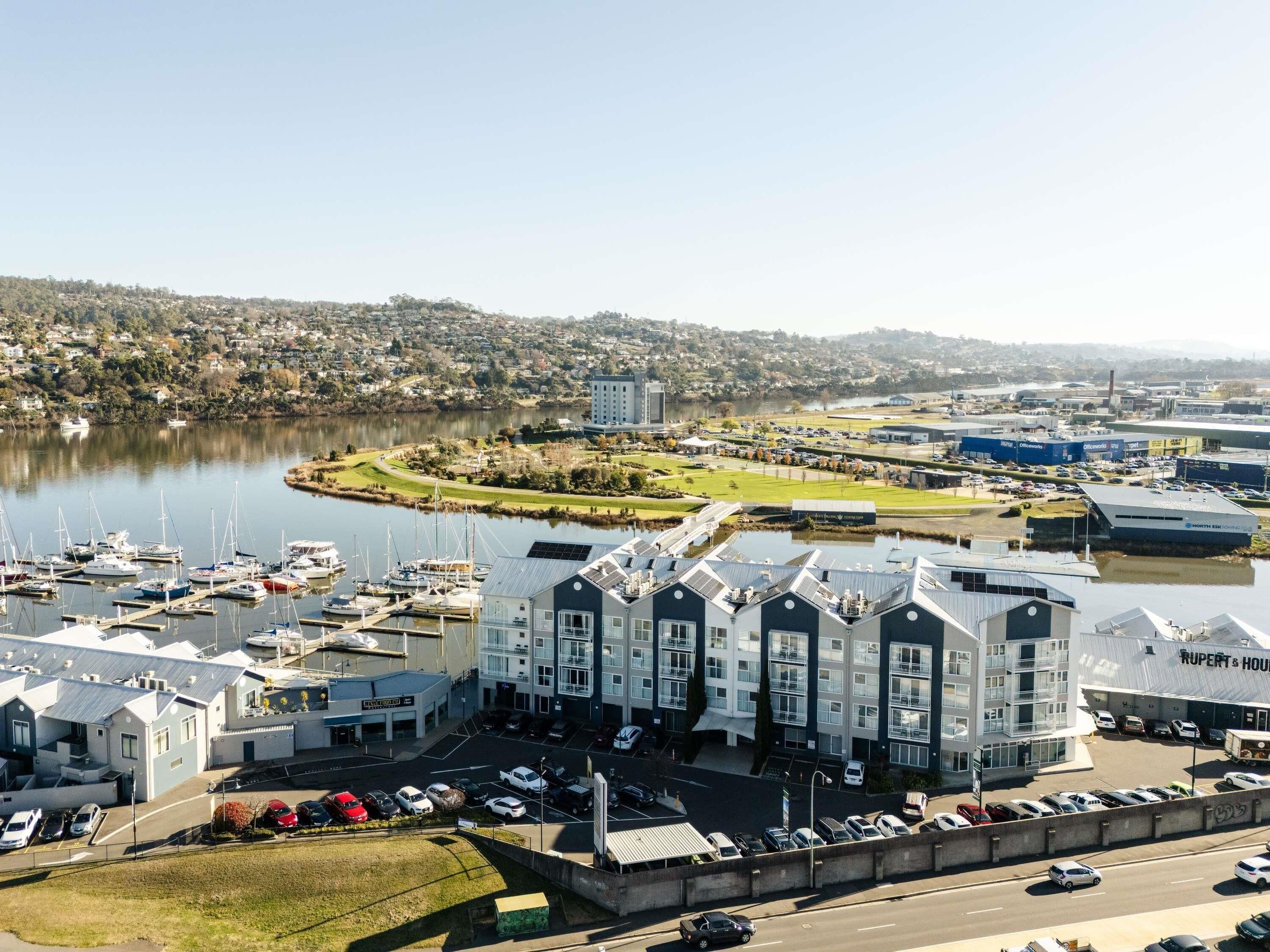 A marina with boats, a large building with 'RUPERT & HOUSTON' signage, and a hilly landscape in the background.