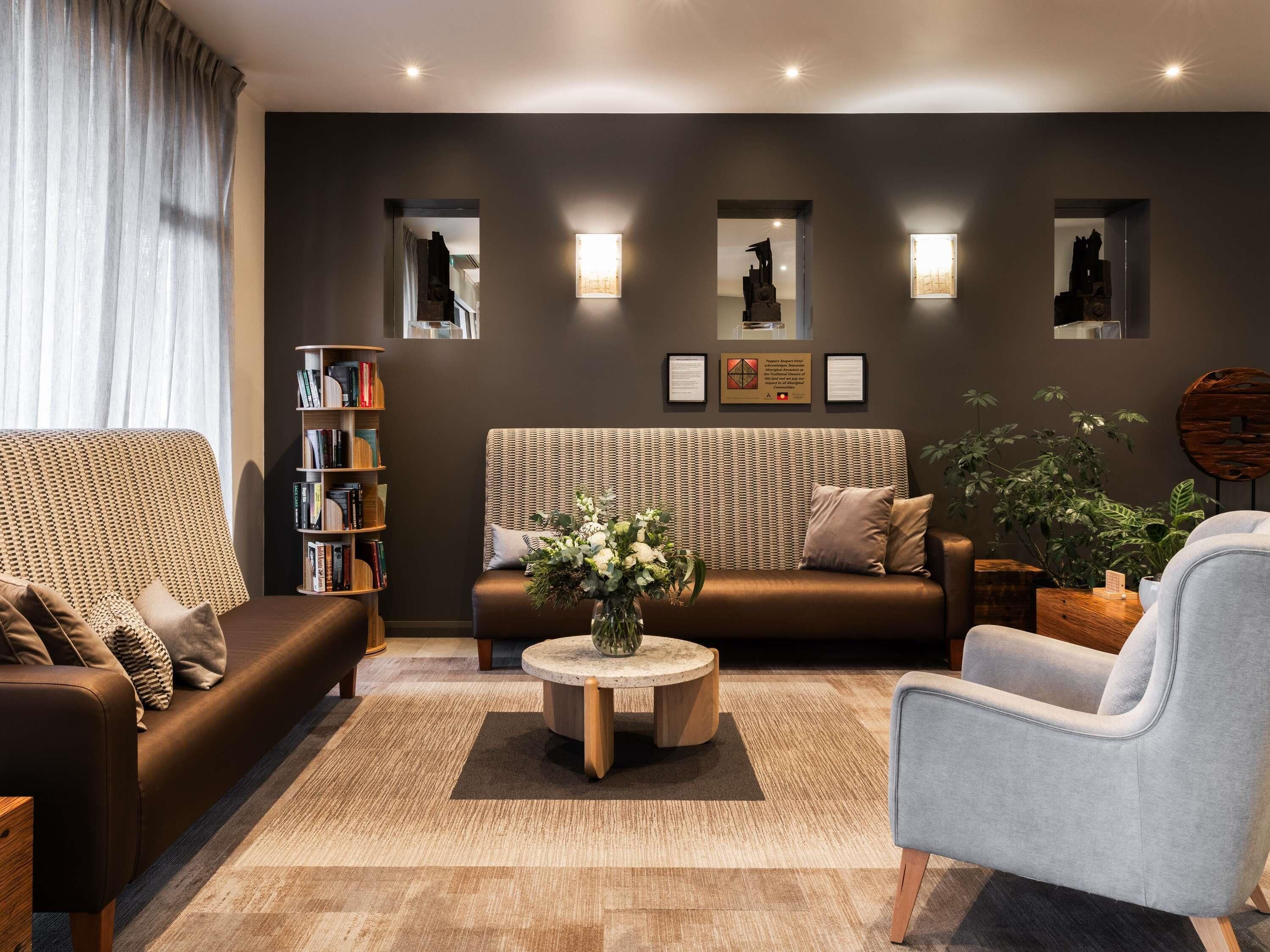 A modern living room with a sofa, armchair, bookshelf, and decorative wall art.
