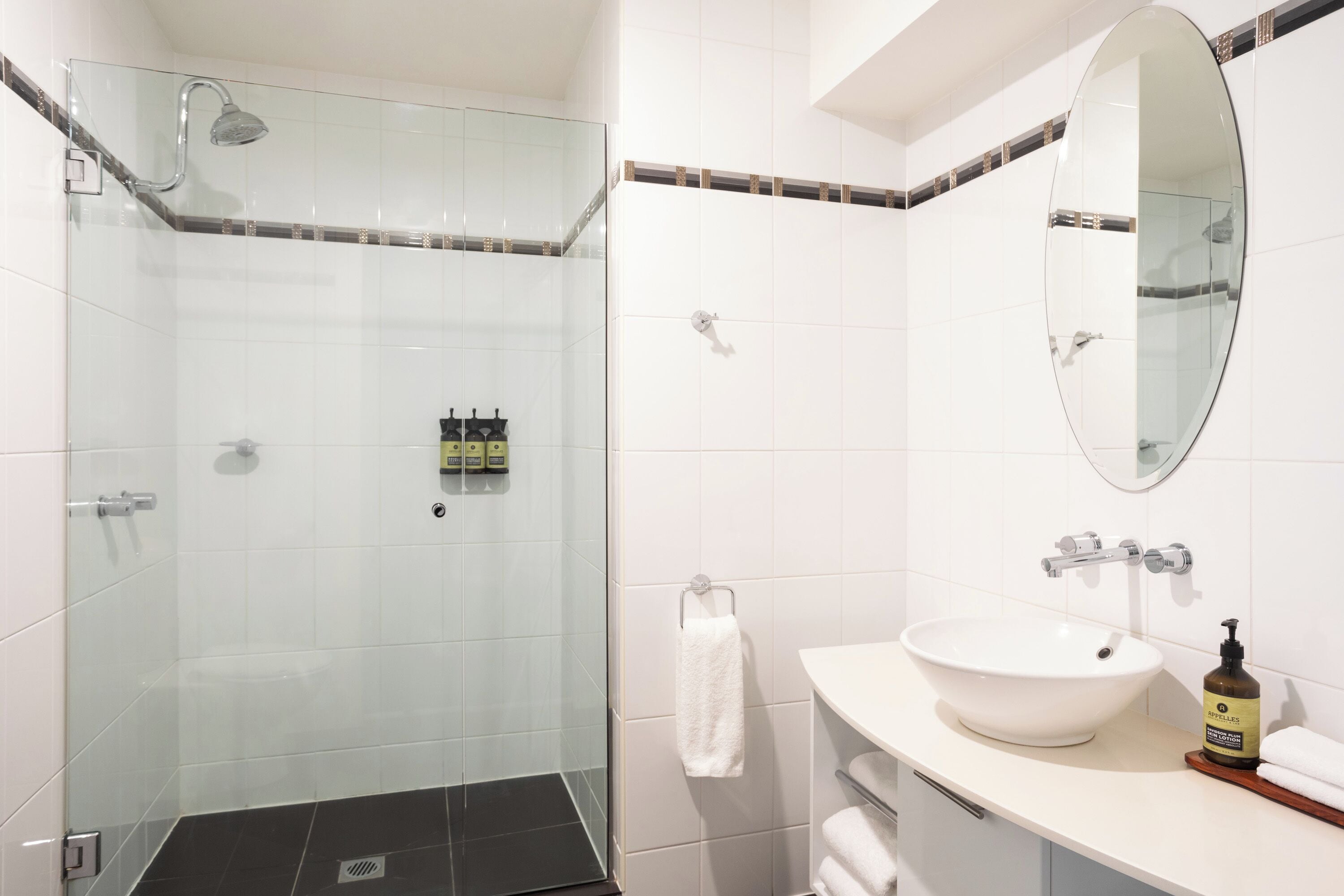 A modern bathroom with a glass-enclosed shower, a white sink, and a mirror above it.