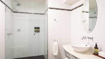A modern bathroom with a glass-enclosed shower, a white sink, and a mirror above it.
