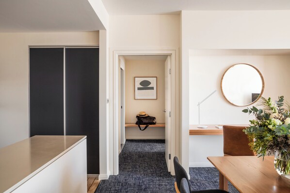 A hotel room with a desk, chair, and a round mirror on the wall.
