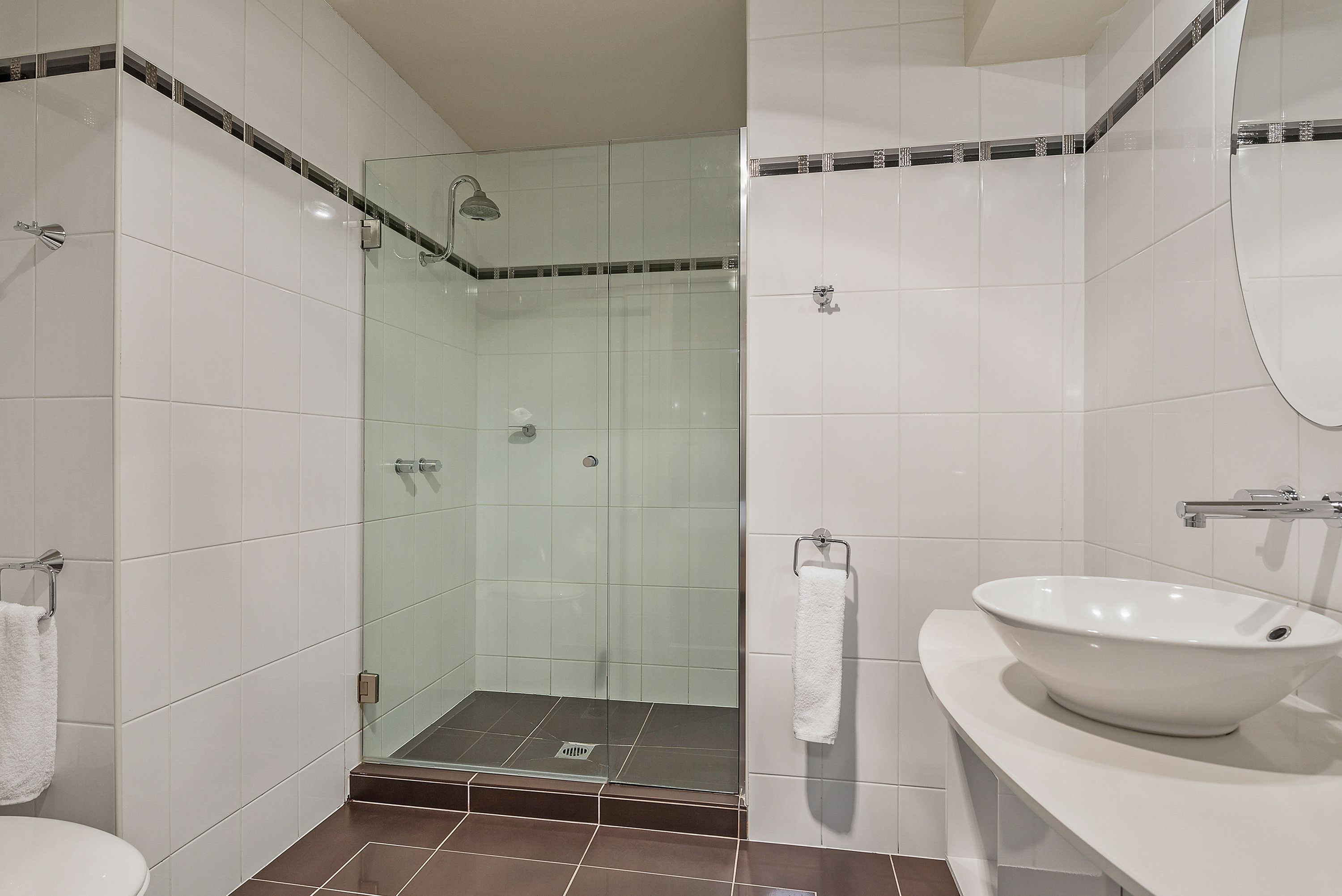 A bathroom with a glass-enclosed shower, a white sink, and a towel rack.