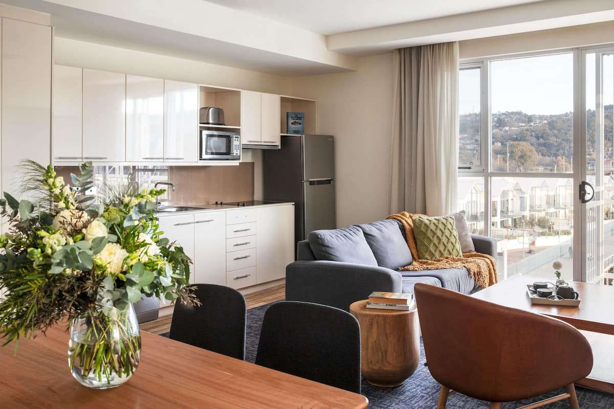 A modern apartment with a kitchen, dining area, and living room with a city view.