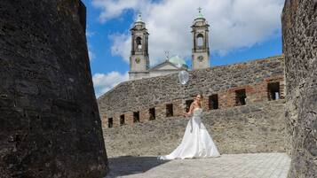 A stone building with two towers and a dome, a bride in a white dress, and a clear sky.