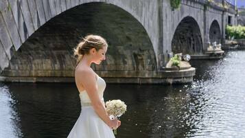 Una persona con un vestido blanco parada junto a un canal con puentes de piedra al fondo.
