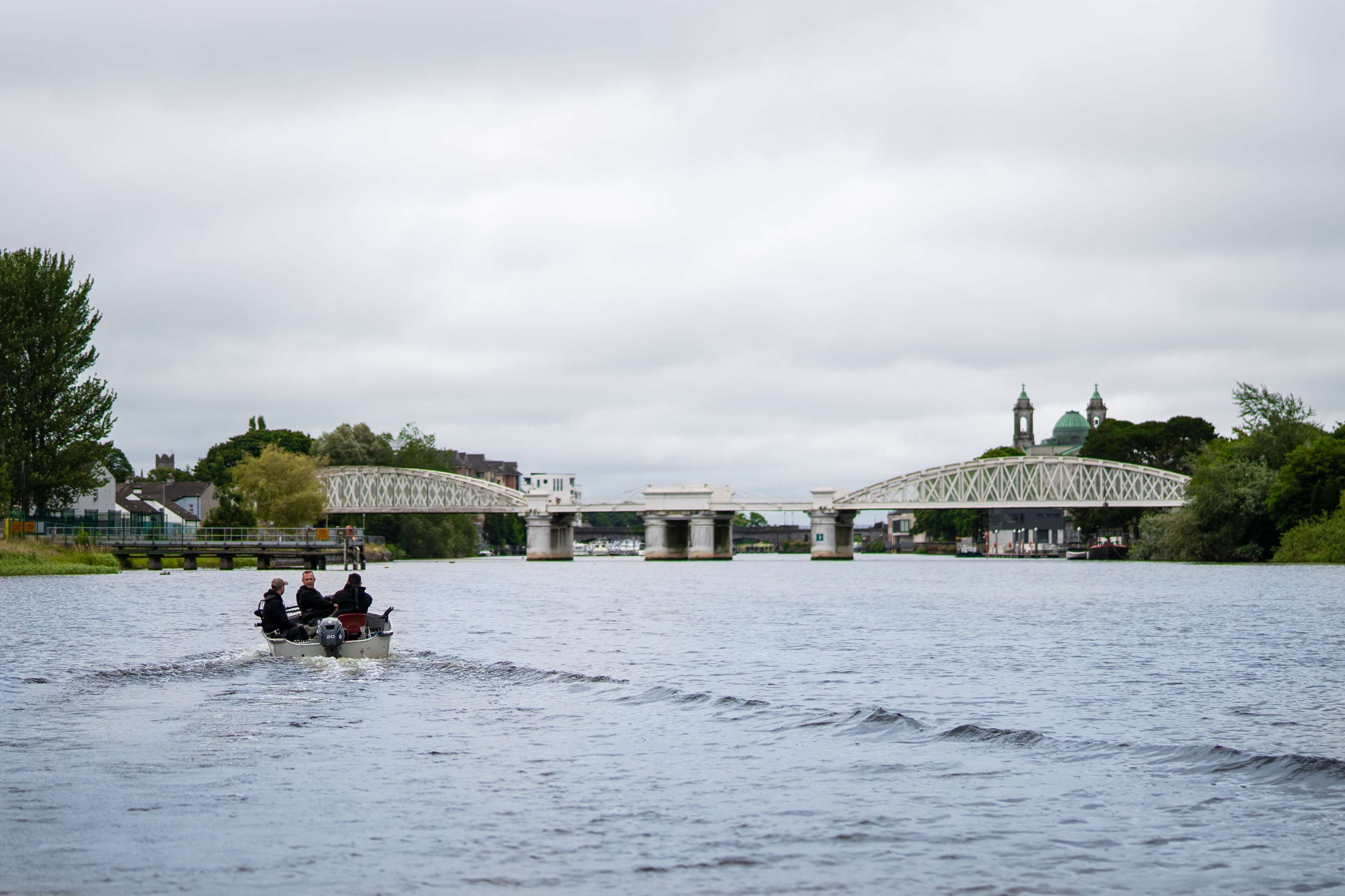 A river with a bridge and a boat carrying passengers.