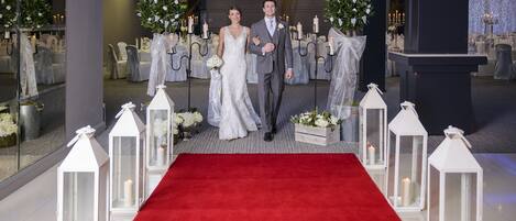 A red carpet aisle with white lanterns and floral arrangements.