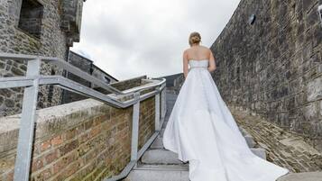 A person in a white wedding dress descending a stone staircase with metal railings.