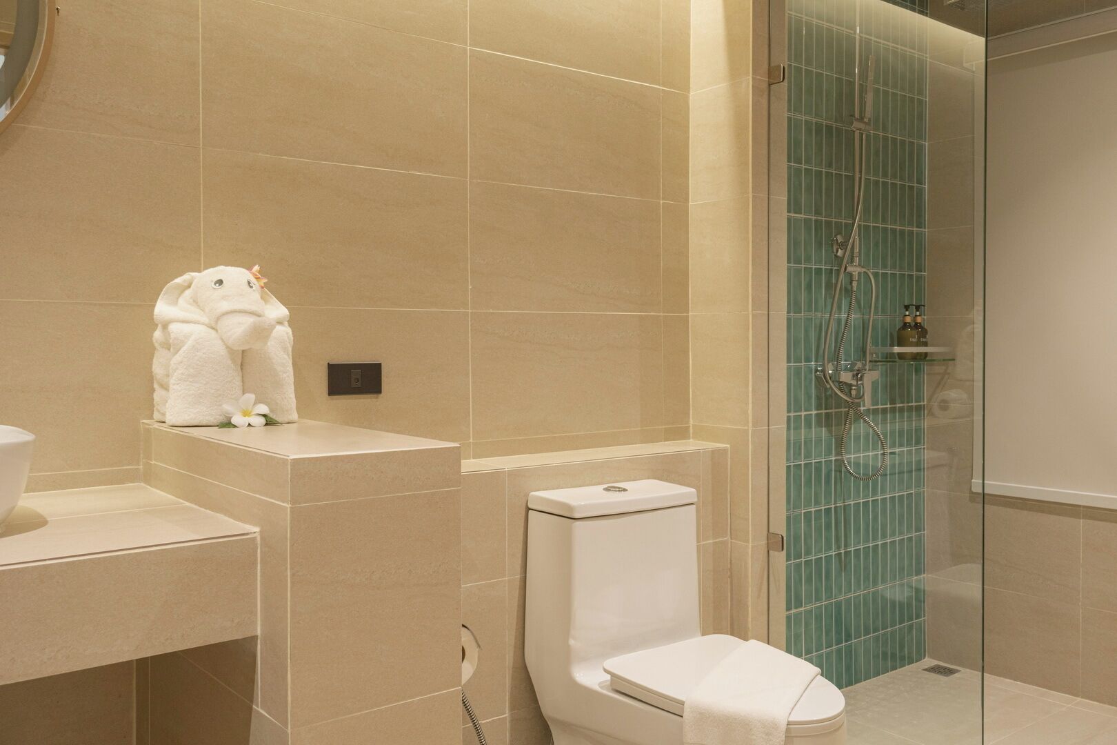 Un baño moderno con inodoro, lavamanos y cabina de ducha con mampara de vidrio.