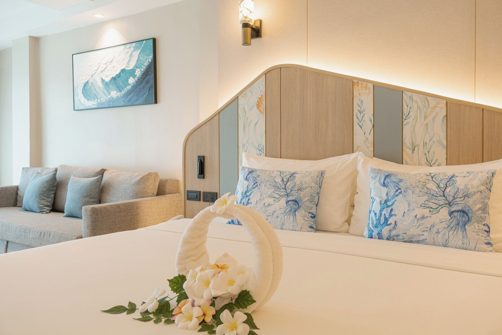 Una habitació d'hotel amb un llit, un sofà, una obra d'art penjada a la paret i una làmpada de paret.