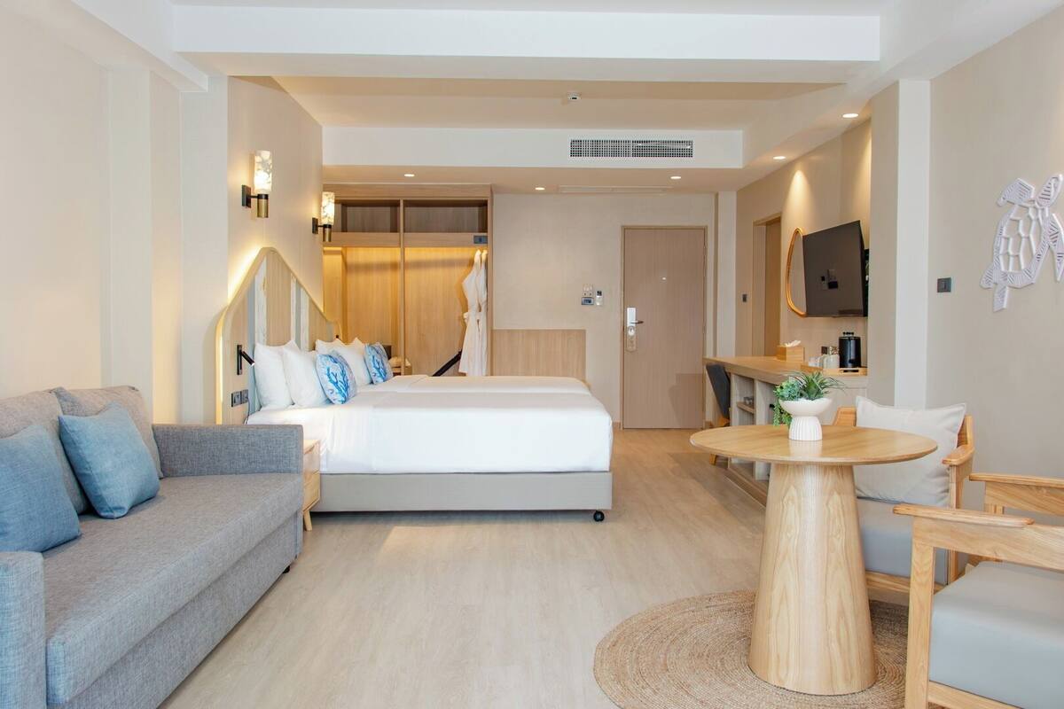 Una habitación de hotel moderna con una cama, un sofá, una mesa de comedor y un televisor.