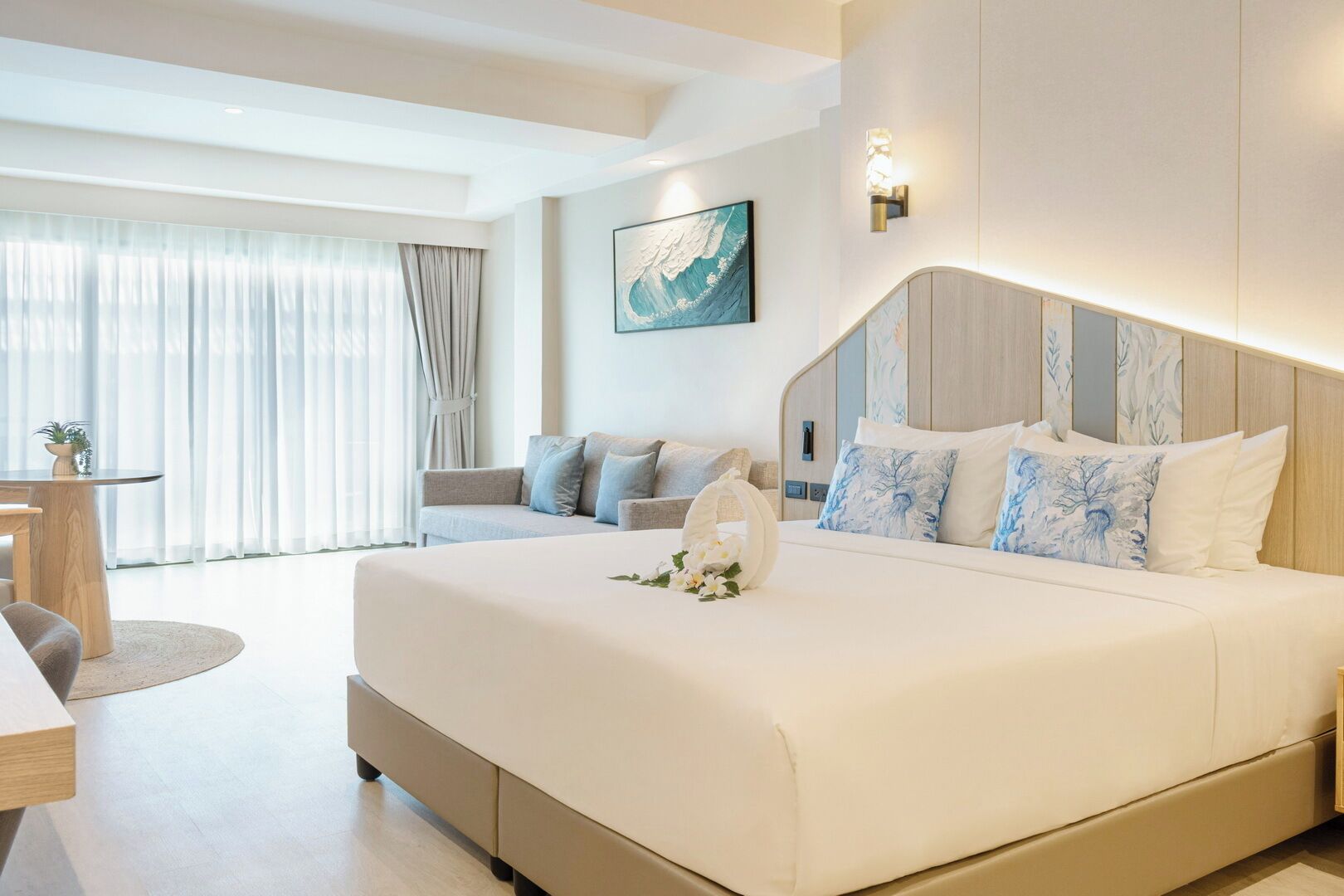 Habitación de hotel moderna con una cama grande, un sofá, una mesa de comedor y vistas al exterior.