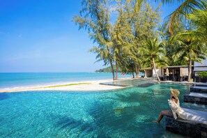A poolside area with clear blue water, a sandy beach, and palm trees. - Khaolak Emerald Beach Resort and Spa (Thai Mueang)