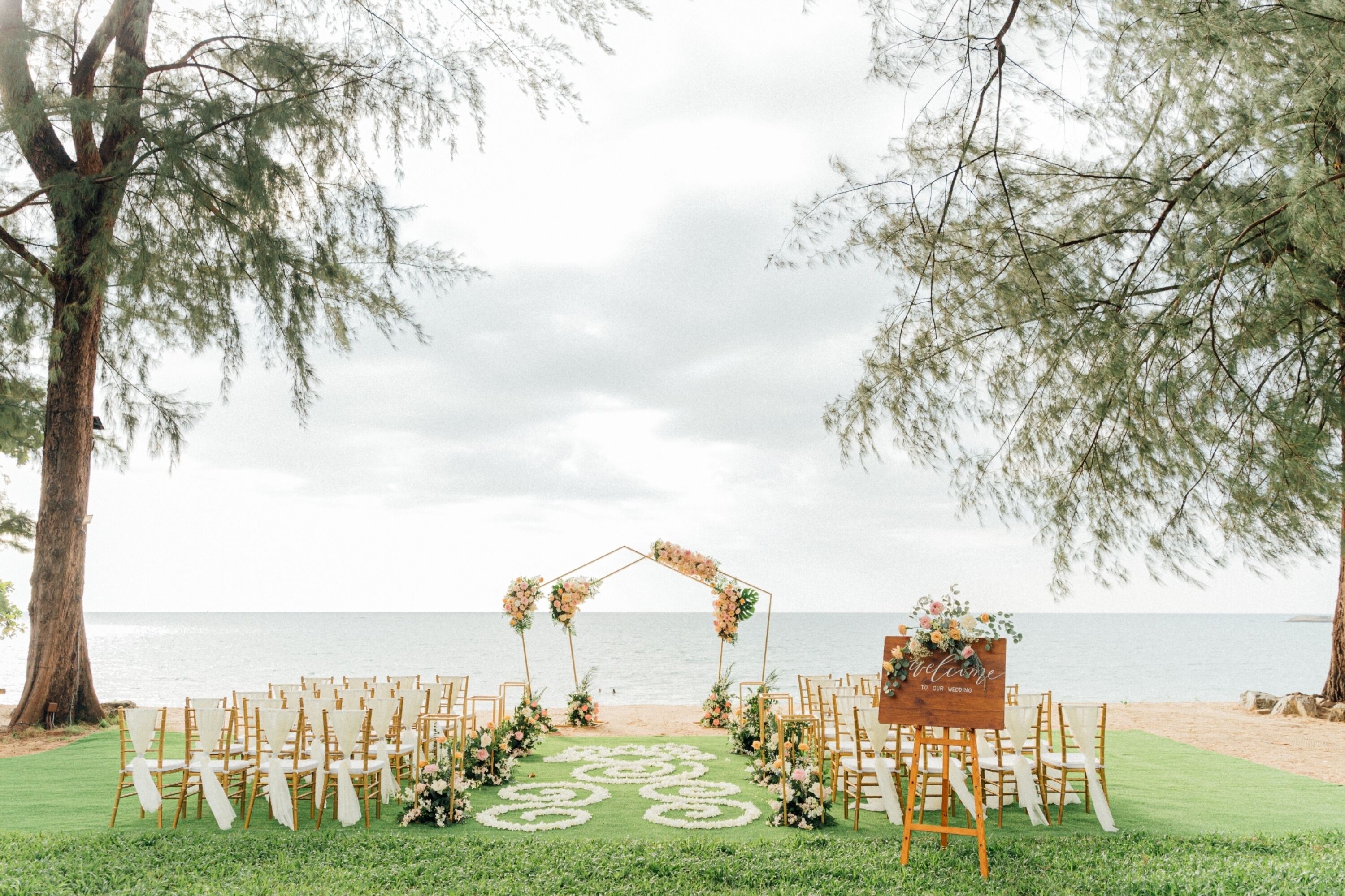 A beach wedding setup with a floral arch and chairs arranged for guests.