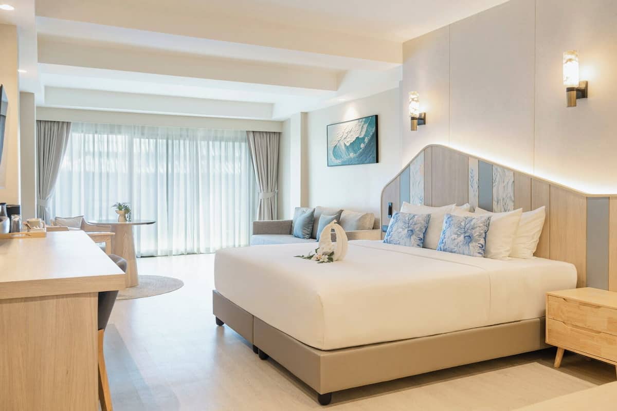 Habitación de hotel moderna con una cama grande, un escritorio y vistas al exterior.
