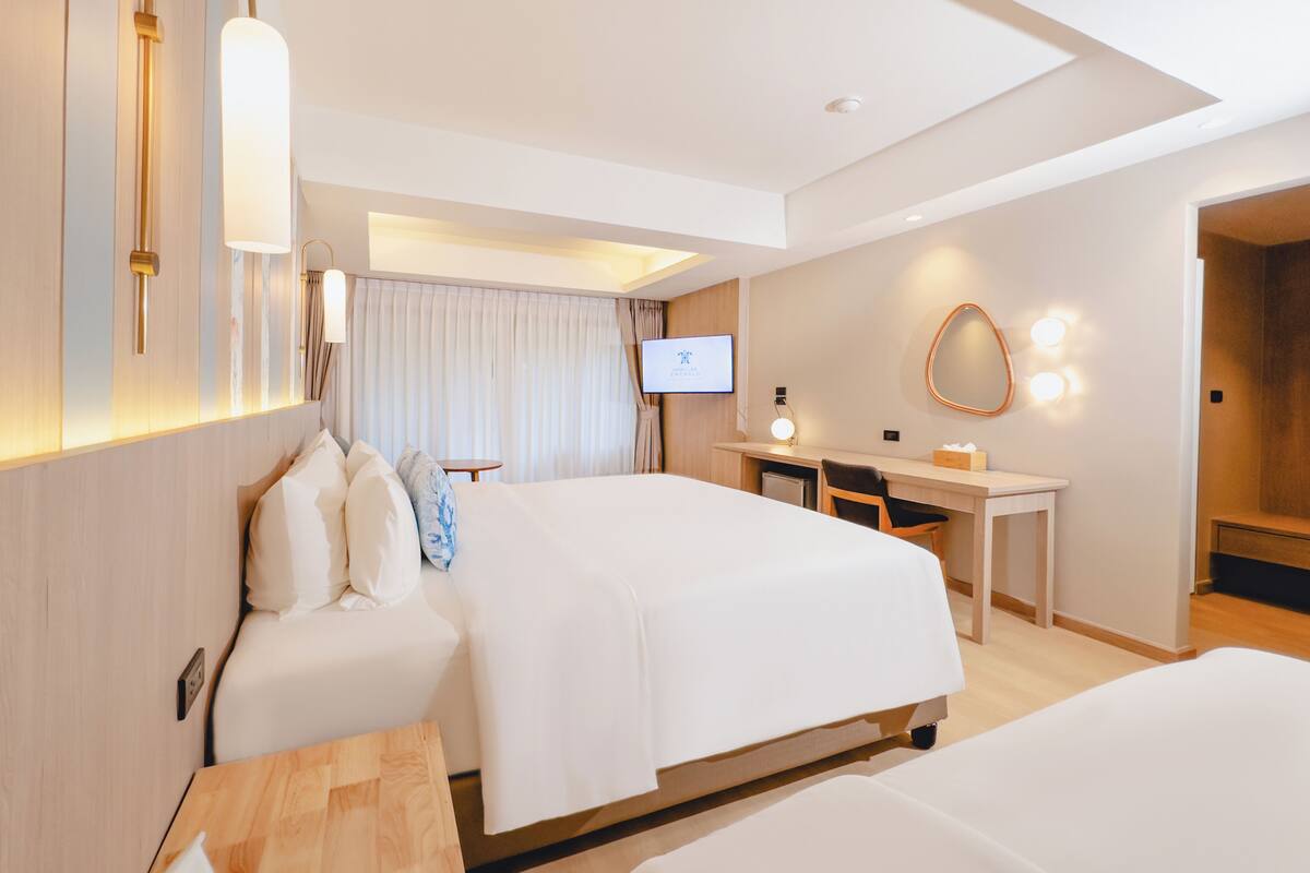 Habitación de hotel con dos camas, un escritorio, un televisor y un espejo.