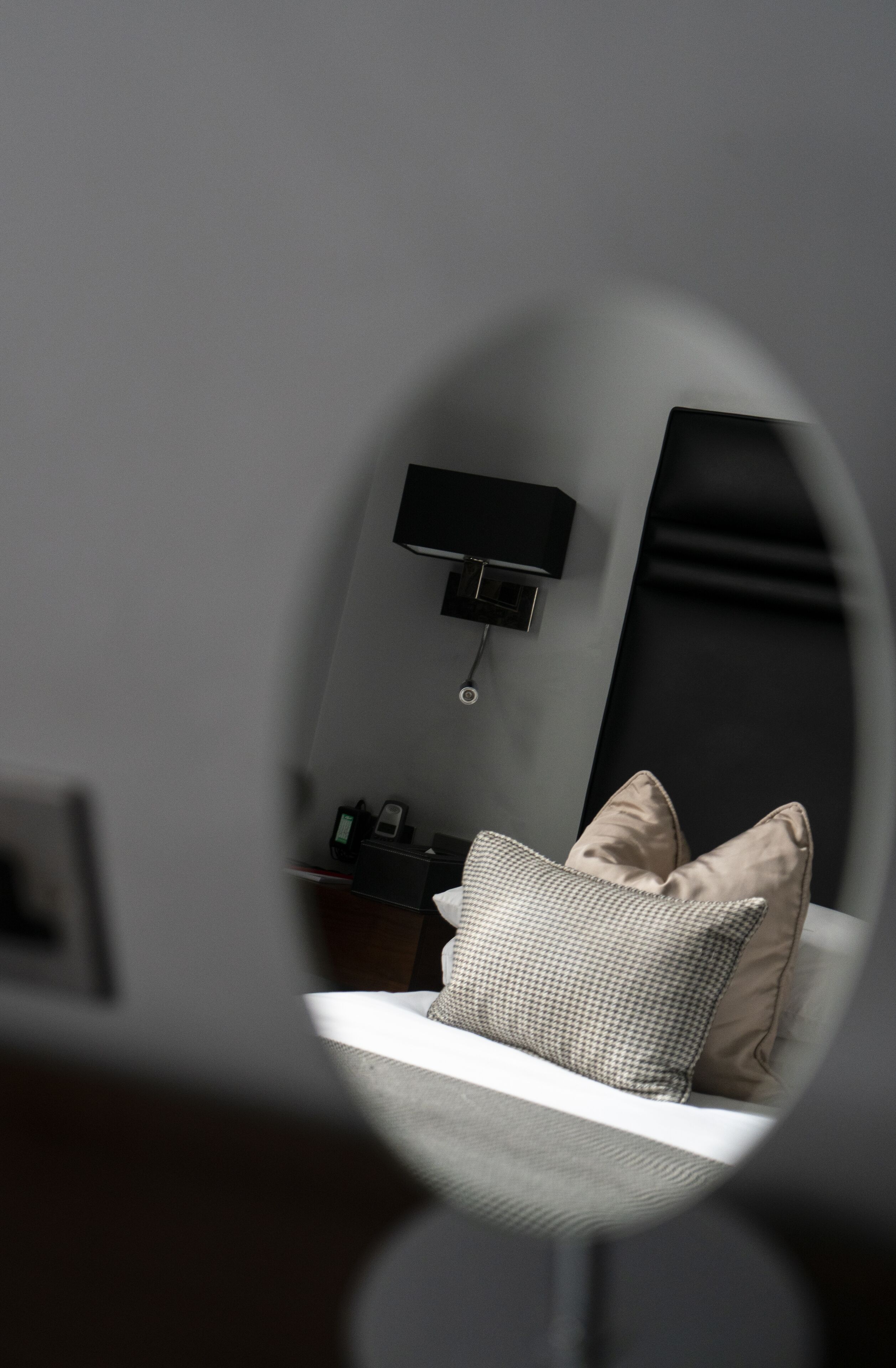 Un dormitorio moderno con cama, mesita de noche, lámpara y estación de carga en la pared.