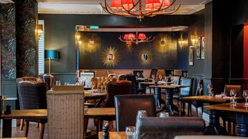 A restaurant with multiple tables and chairs, a chandelier, and wall decorations.