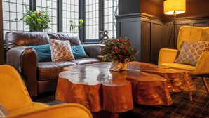 A modern living room with a leather sofa, wooden coffee table, and yellow armchairs. - Balmer Lawn Hotel (Brockenhurst)