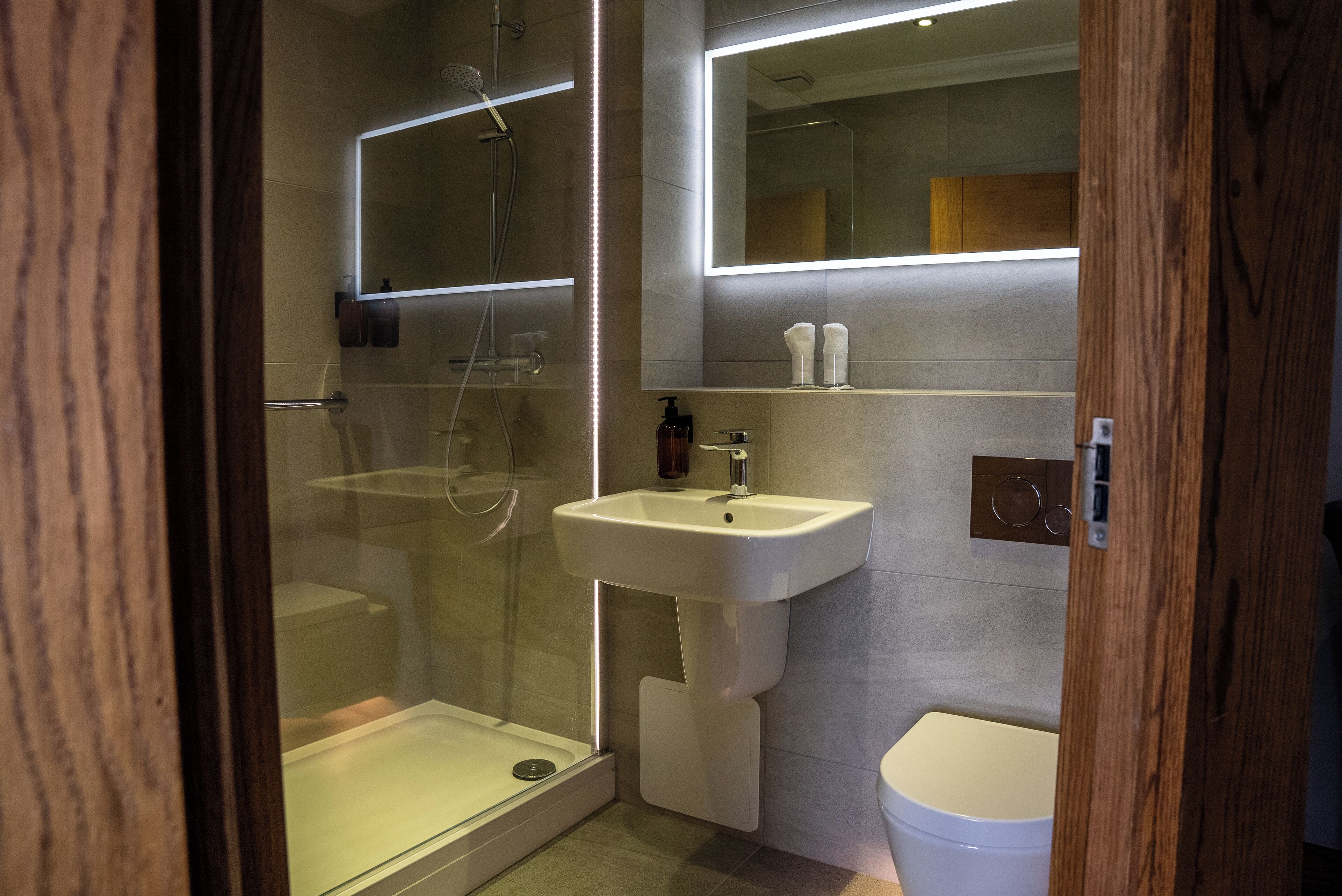 Ein modernes Badezimmer mit einer gläsernen Duschkabine, einem weißen Waschbecken und einer Toilette.