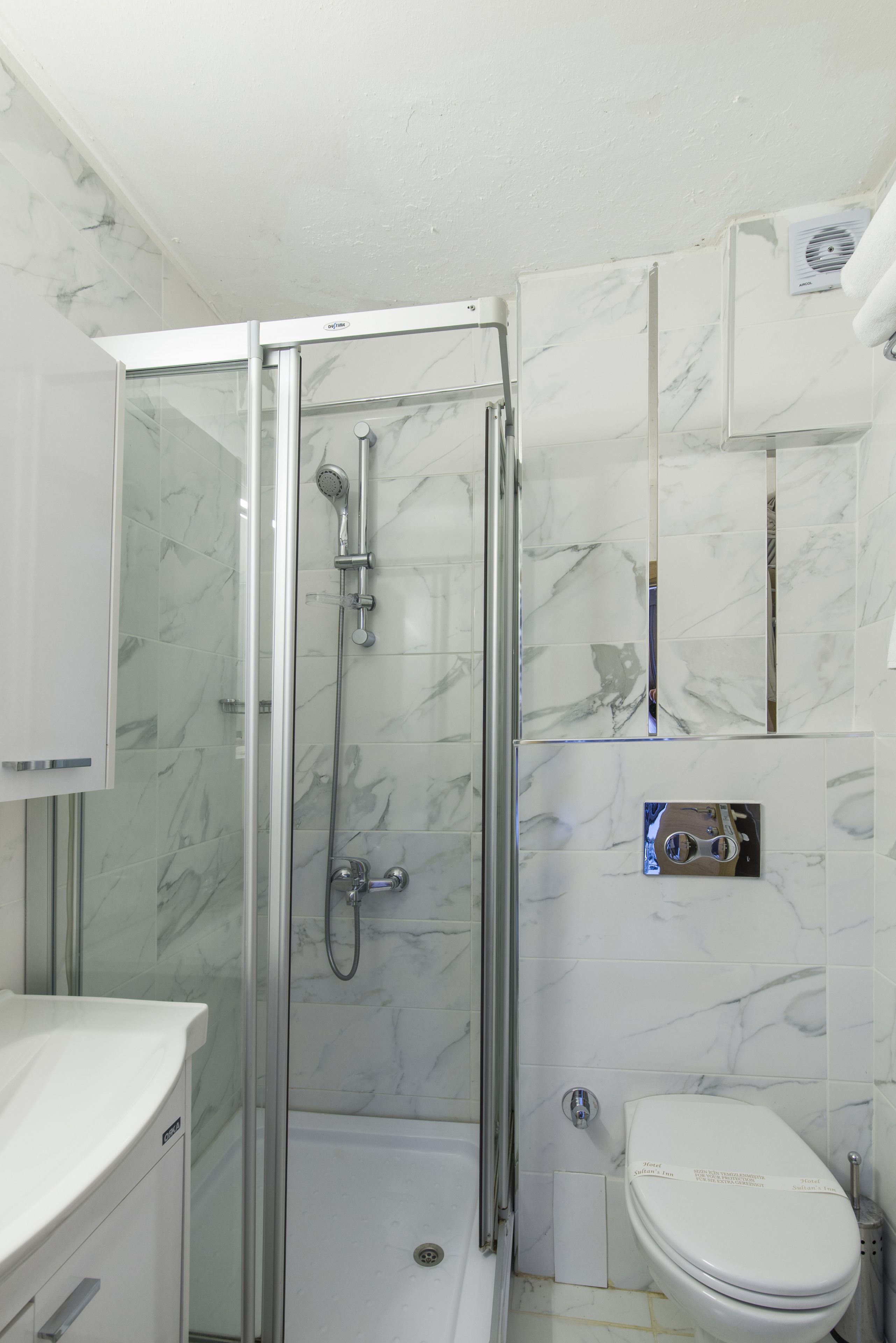 Een badkamer met een douchecabine van glas, een toilet en een wastafel.