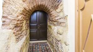 A stone archway leading to a dark wooden door, with a patterned rug on the floor. - Naz Wooden House Inn - Byzantine House (Istanbul)